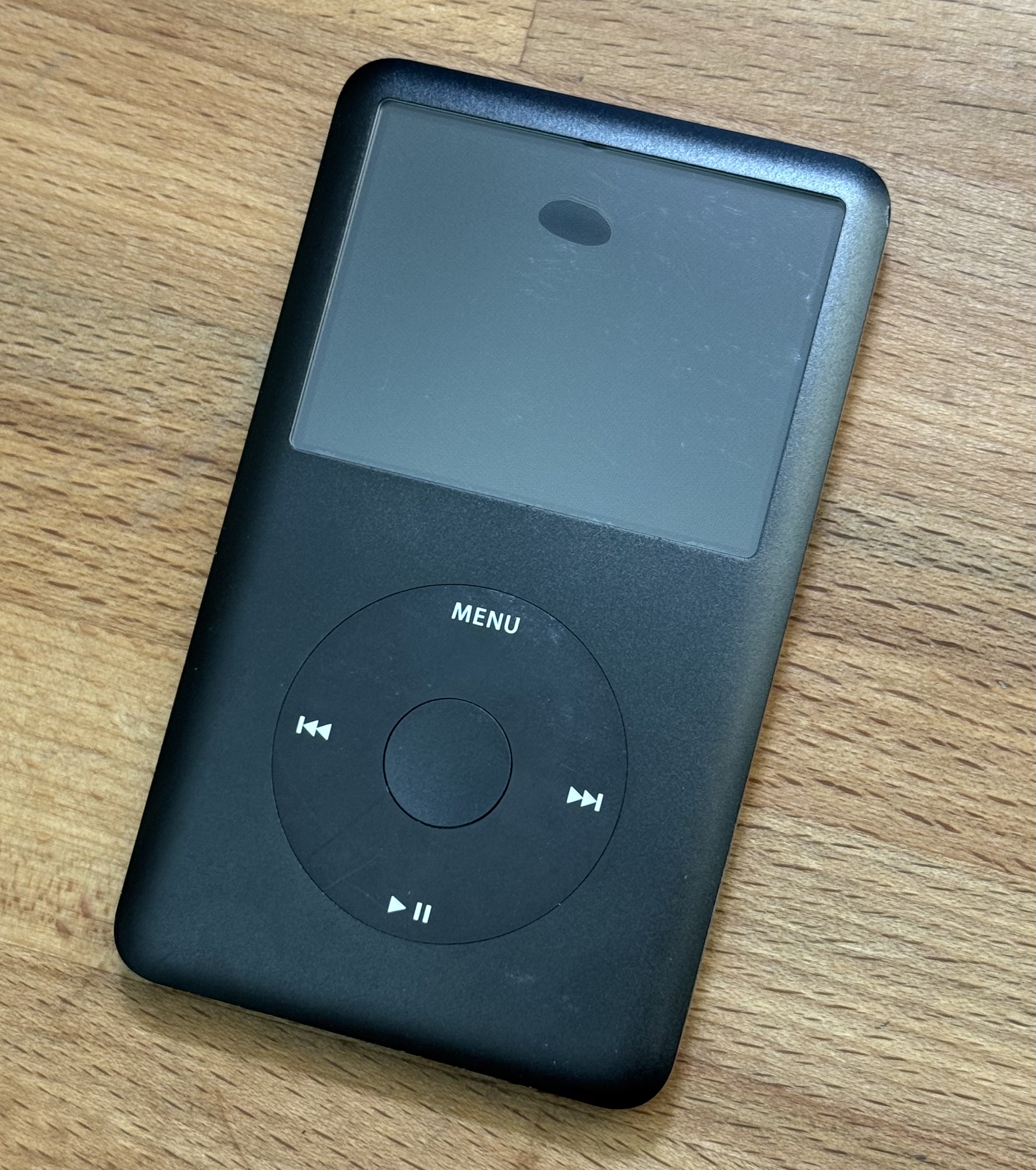 Black iPod Classic with a dark bubble near the upper center of its display